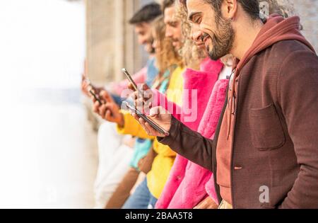 Groupe de personnes debout regardant multiraciale avec leur téléphone cellulaire. Les jeunes toujours connecté à l'internet et du réseau social de concept. Droit Banque D'Images