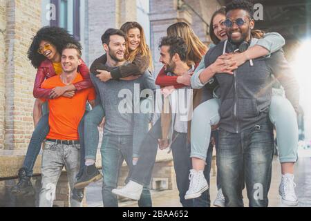 Quatre couples multiraciaux s'amusant sur le dos sous l'arcade en ville le matin. Les élèves s'amuser dans la ville. Banque D'Images