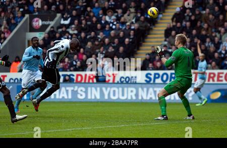 Demba Ba (à gauche) de Newcastle United obtient son premier but du jeu après le gardien de but de Manchester City Joe Hart (à droite) Banque D'Images