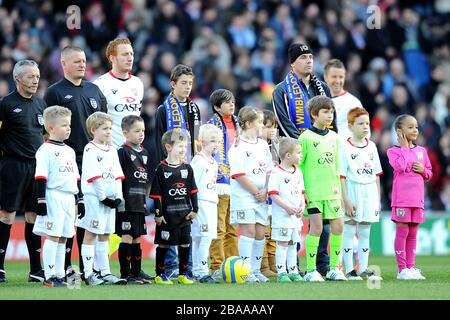 Les mascottes Milton Keynes Dons s'alignent avec les officiels du match avant le lancement Banque D'Images