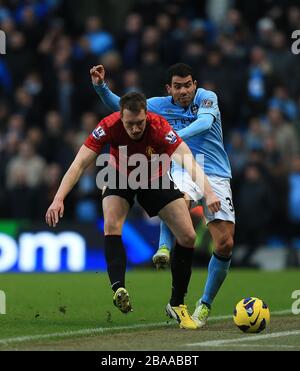 Carlos Tevez de Manchester City (à droite) et Phil Jones de Manchester United affrontent le ballon Banque D'Images