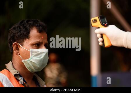 Guwahati, Assam, Inde. 26 mars 2020. Le personnel de police contrôle thermique une personne avant d'entrer au gouverneur House pour vaporiser du désinfectant, à Guwahati. Crédit: David Talukdar/ZUMA Wire/Alay Live News Banque D'Images