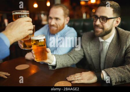 Groupe d'hommes qui toaster avec des verres de bière pendant une réunion dans un café et se reposer après le travail Banque D'Images