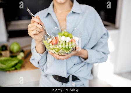 Femme mangeant une salade saine sur la cuisine à la maison, vue courte sans visage. Concept de saine alimentation, de nourriture et de style de vie Banque D'Images