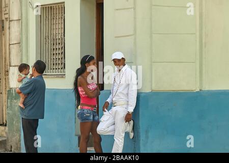 Jeune homme cubain portant tous les vêtements blancs Santeria traditionnels penchant sur le mur en discussion avec sa petite amie au Centro Havana Banque D'Images