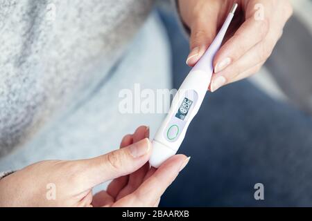 Thermomètre à main pour femme présentant une température corporelle élevée Banque D'Images
