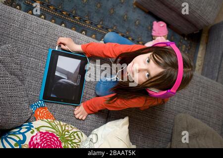 Fille de 6 ans portant des écouteurs regardant son iPad, Angleterre Banque D'Images