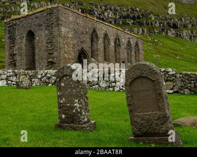 Îles Féroé. Village de Kirkjubøur. Vieilles ruines jamais toits de la cathédrale médiévale. Pierres tombales dans l'ancien cimetière. Banque D'Images