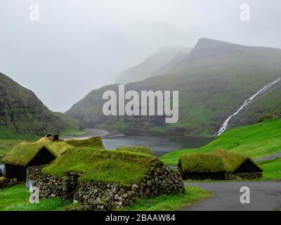 Îles Féroé. Paysage naturel nordique, Saksun, île de Stremnoy. Danemark. Maisons de toit vert emblématiques. Dans la vallée de fond et la chute d'eau. Banque D'Images