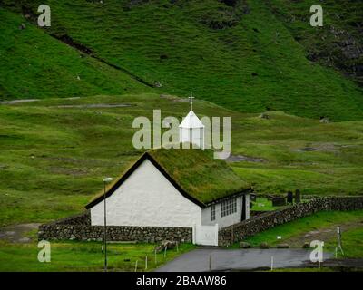 Îles Féroé, Streymoy, Saksun. Vue sur l'église et la vallée de Saksun. Bâtiment blanc avec toit en herbe debout hors des champs verts. Banque D'Images