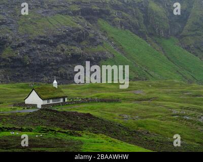 Îles Féroé, Streymoy, Saksun. Vue sur l'église et la vallée de Saksun. Bâtiment blanc avec toit en herbe debout hors des champs verts. Banque D'Images