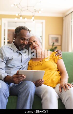 Couple afro-américain senior utilisant une tablette numérique dans un canape Banque D'Images