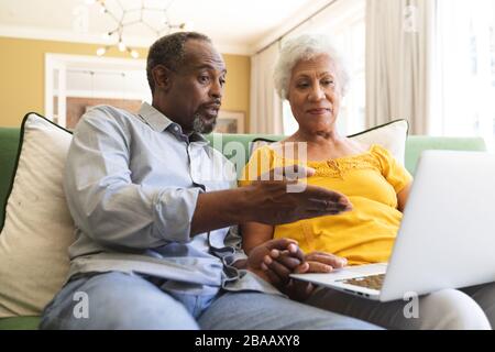 Couple afro-américain senior utilisant un ordinateur portable dans un canape Banque D'Images