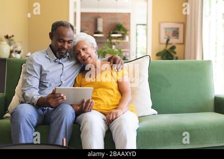 Couple afro-américain senior utilisant une tablette numérique dans un canape Banque D'Images