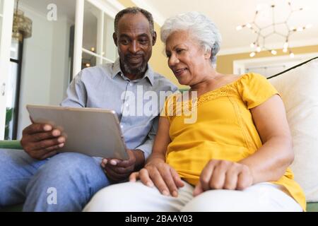 Couple afro-américain senior utilisant le numérique dans un canape Banque D'Images