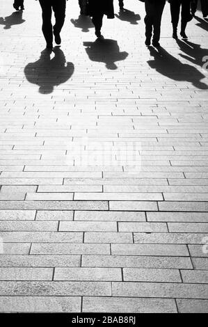 Contexte d'affaires des voyageurs d'affaires et de leurs ombres qui ne sont pas reconnaissables se promenant sur une passerelle en briques propres Banque D'Images