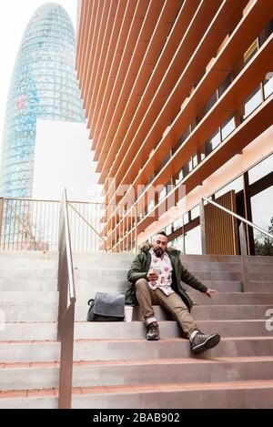 Beau jeune homme vêtu de façon décontractée passer du temps à l'extérieur avec mobile Banque D'Images