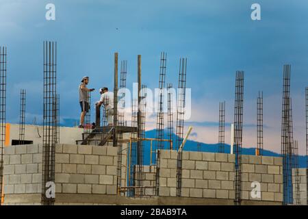 Deux ouvriers du bâtiment travaillent ou sur le toit, soudant des rails métalliques. Banque D'Images