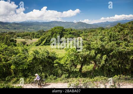 Homme âgé poussant à vélo le long de la route de terre, Guatemala. Banque D'Images