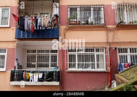 Istanbul, Turquie - 12 février 2020: La façade d'un immeuble d'appartements avec fenêtres barrées et cordes pour sécher des vêtements mouillés en plein air. Banque D'Images