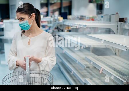 Femme portant un masque de visage acheter dans un supermarché/pharmacie avec des fournitures vendues.Shopper panique acheter et hoarding conduisant à l'insoutenable marché.W Banque D'Images
