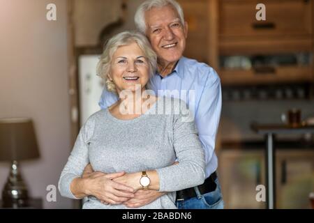 Heureux couple senior embrassant dans leur maison Banque D'Images
