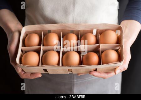 Oeufs de poulet crus dans les mains de la femme. Banque D'Images