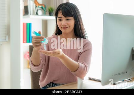 Femme asiatique utilisant fréquemment des mains de nettoyage de gel antiseptique d'alcool, prévenir l'infection, éclosion de Covid-19 se laver les mains avec de l'aseptisant tout en utilisant la comp Banque D'Images