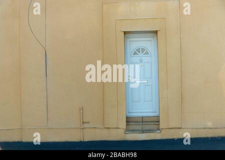 vue rapprochée d'une porte avant blanche où le mur autour de celle-ci est de couleur jaune doux Banque D'Images