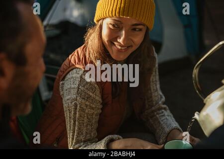 Homme qui verse du café dans la tasse de la femme au camping. Couple camping dans la nature ayant du café. Banque D'Images