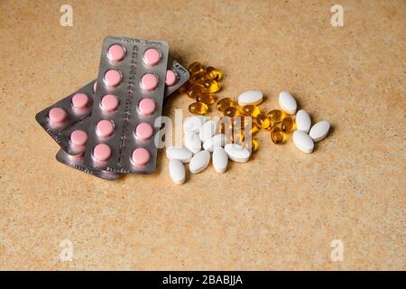 capsules ambrées, roses et blanches sur une table avec un motif de sable Banque D'Images