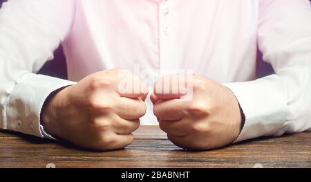 Un homme tient ses poings fermés sur la table. Une attaque de colère, de stress. Un geste décisif et émotionnel. Hommes impulsifs. Souffrir de la défaite, de l'échec et des los Banque D'Images