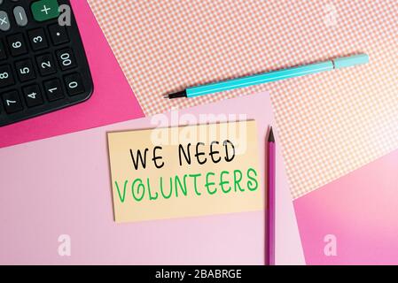 Note d'écriture montrant que nous avons besoin de bénévoles. Concept d'affaires pour quelqu'un qui travaille sans être payé pour les équipements d'écriture informatique et papier à note ordinaire Banque D'Images