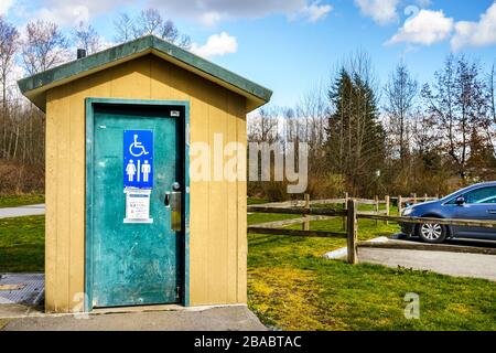 Surrey, Canada - 25 mars 2020 : toilettes extérieures au parc régional de Tynehead, dans le métro de Vancouver, avec des renseignements sur la santé du virus Corona affichés à la porte Banque D'Images