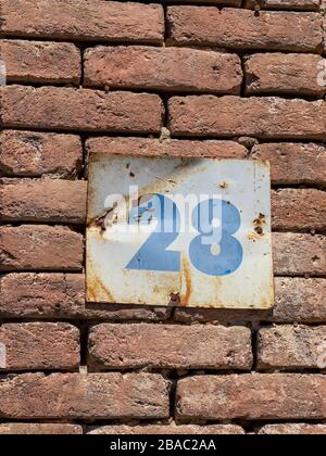 Rue numéro 28 sur un placarde métal contre un mur de briques, numéros bleus sur un fond blanc Banque D'Images