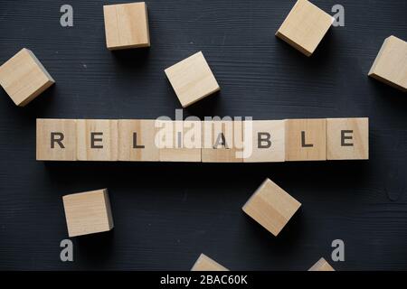 Mot à la mode moderne pour les entreprises - fiable. Vue sur la table en bois avec des blocs. Vue de dessus. Gros plan. Banque D'Images