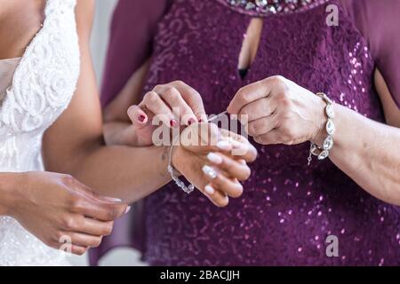 La mère de mariée l'aidant à porter des bijoux de mariage Banque D'Images