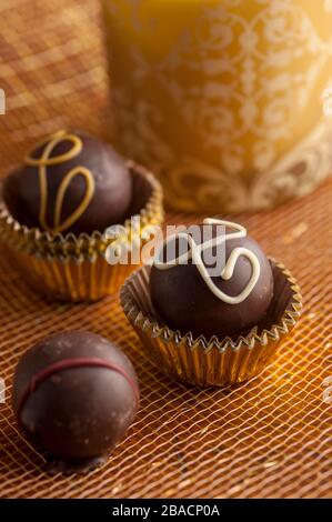 Truffes au chocolat noir en tasses d'or avec fond doré tourné dans le studio. Banque D'Images