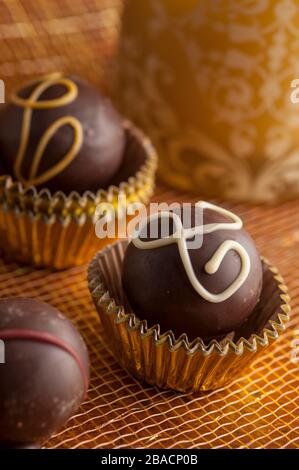 Truffes au chocolat noir en tasses d'or avec fond doré tourné dans le studio. Banque D'Images