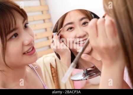 Sourcils amies au miroir dans la chambre Banque D'Images