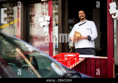Weil am Rhein, Allemagne. 26 mars 2020. Le maître boulanger Simon Fritz se tient dans la fenêtre de la conduite improvisée de sa boulangerie et tient un pain dans sa main. Le commerce de détail est déjà aux prises avec les conséquences de l'épidémie de corona et la baisse des ventes qui y est associée. Crédit: Philipp von Ditfurth/dpa/Alay Live News Banque D'Images