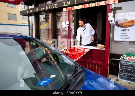 Weil am Rhein, Allemagne. 26 mars 2020. Maître boulanger Simon Fritz glisse un sac à un client de la fenêtre de la conduite improvisée de sa boulangerie. Le commerce de détail est déjà aux prises avec les conséquences de l'épidémie de corona et la baisse des ventes qui y est associée. Crédit: Philipp von Ditfurth/dpa/Alay Live News Banque D'Images