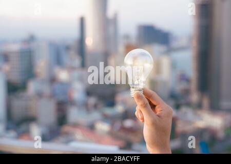 Coucher du soleil au-dessus de l'ampoule ampoule maisons urbaines. lampe transparent sur l'énergie solaire en milieu urbain, la cité, la ville de la vie nocturne. Symbole, concept de busi Banque D'Images