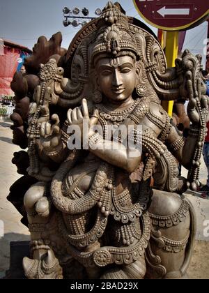 Statue impressionnante de Lord Krishna sculptée dans un bloc de bois unique exposé à la foire artisanale de Surajkund, en Inde Banque D'Images