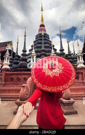 Femme avec parapluie traditionnel Thaï rouge homme tenant à la main et d'aller à Black temple Wat Phan Tao dans Chiang Mai, Thaïlande Banque D'Images