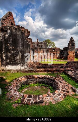 Les murs en ruine antique et bien de Temple à Lopburi, Thaïlande ciel au coucher du soleil Banque D'Images