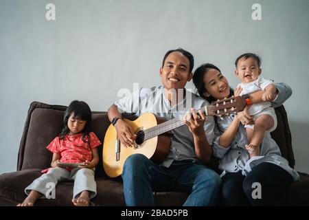le père a joué de la guitare pour remplir les activités tout en restant à la maison, la mère et le fils ont chanté avec joie Banque D'Images