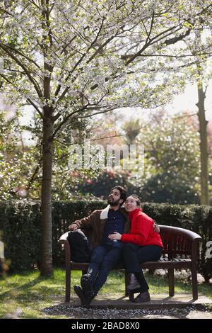 Ruslan Thaher et Marissa Szabo s'assoient sous des arbres en fleurs dans le jardin de Kyoto à Holland Park, Londres. Le National Trust incite les gens à célébrer la saison des fleurs au Royaume-Uni, en incargeant une ancienne tradition japonaise qui marque l'arrivée du printemps, en encourageant les gens qui peuvent voir des arbres de la fenêtre, dans leur jardin ou dans la rue en pleine floraison à faire une pause et à profiter de la vue, et de partager leurs images sur les réseaux sociaux pour ceux qui ne peuvent pas les voir. Banque D'Images