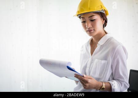 Les femmes asiatiques et l'inspection technique et de travail holding blueprints at office Banque D'Images