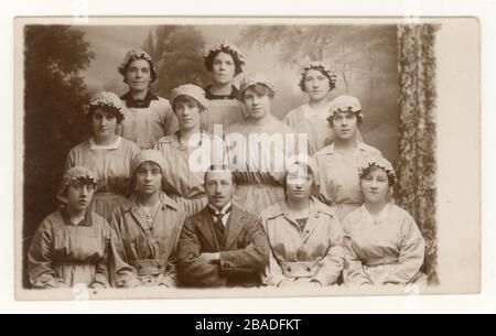 Original de WW1 ans portrait de studio carte postale de groupe de femmes civiles de munitions avec le directeur, l'une des filles porte un badge "on War Service", Angleterre, Grande-Bretagne, Royaume-Uni Circa 1916, 1917 ou 1918 Banque D'Images